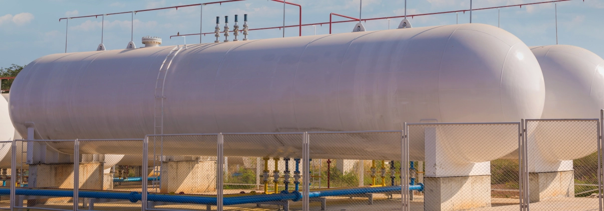 Sıvılaştırılmış gaz tankları periyodik kontrol ve muayene için hazır durumda, açık hava tesisinde güvenlik çiti ile çevrili büyük yatay tanklar.